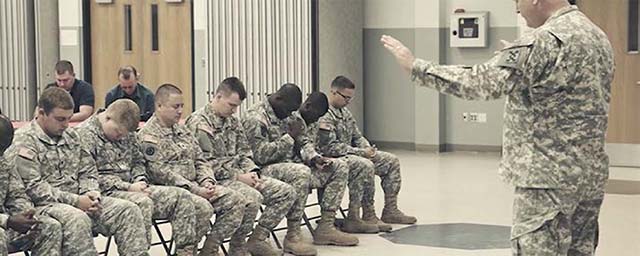 Picture of Chaplain praying over soldiers.